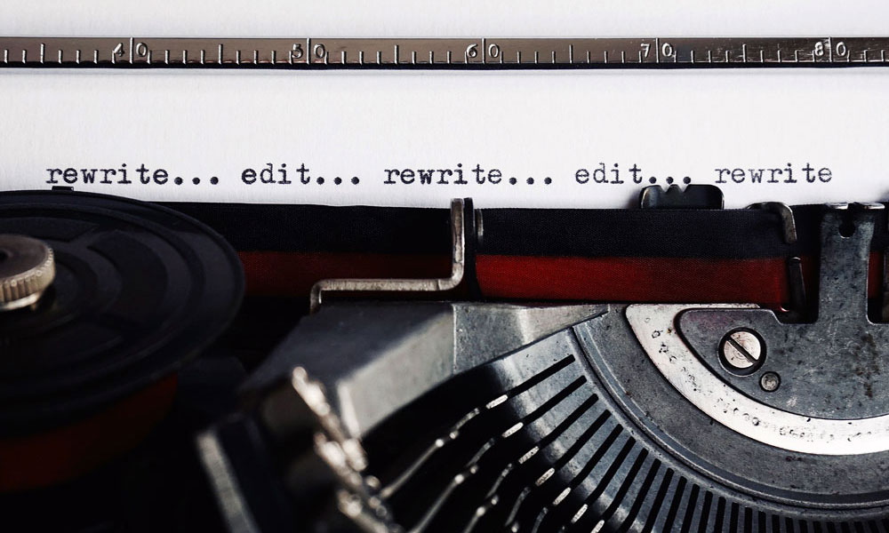 An old fashioned typewriter containing piece of paper that says rewrite... edit... rewrite... edit... rewrite