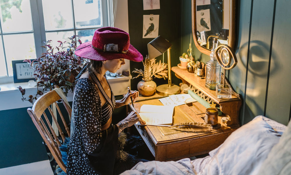 A creatively dressed young woman sitting at a writing desk